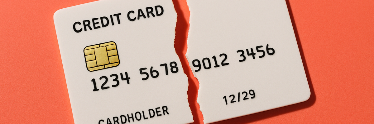A cream-colored credit card snapped in half on an orange background.