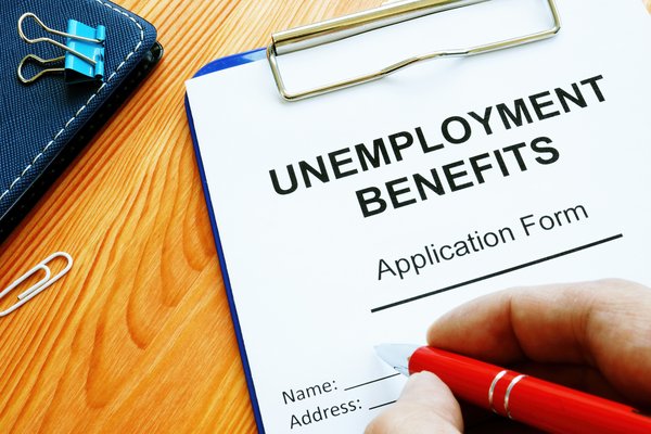 Person filling out unemployment benefits application form.