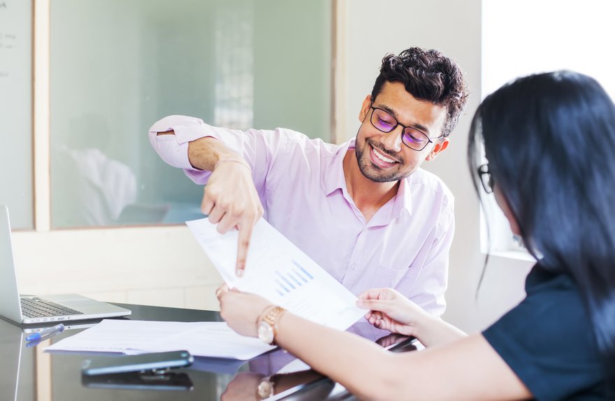 Two people in office looking at paper with bar chart.