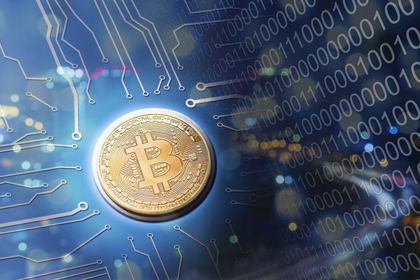 Cold goin with a Bitcoin symbol sitting on a blue circuit board.