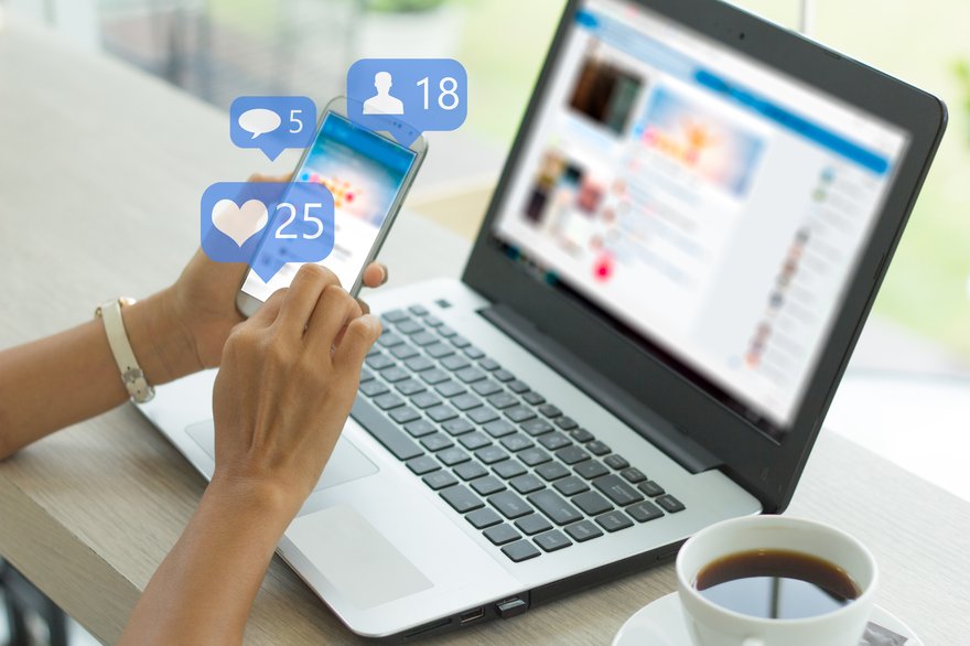 A person using social media on a smartphone and laptop.