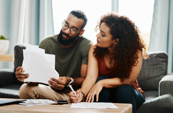 Two individuals review paperwork at home.
